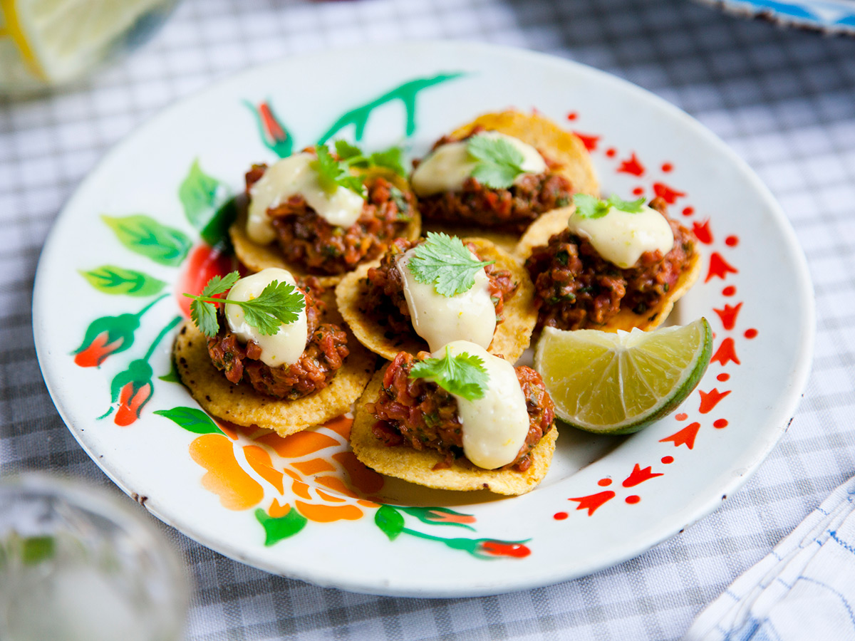 Bistek auf Mais-Tortilla-Chips: Saftiges Rinderfilet mit frischem Koriander und Gewürzen, serviert auf knusprigen Chips, dazu Mayonnaise.